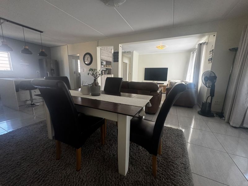 An open-plan living and dining area featuring tiled flooring, a kitchen island with pendant lighting, and a connected lounge space.