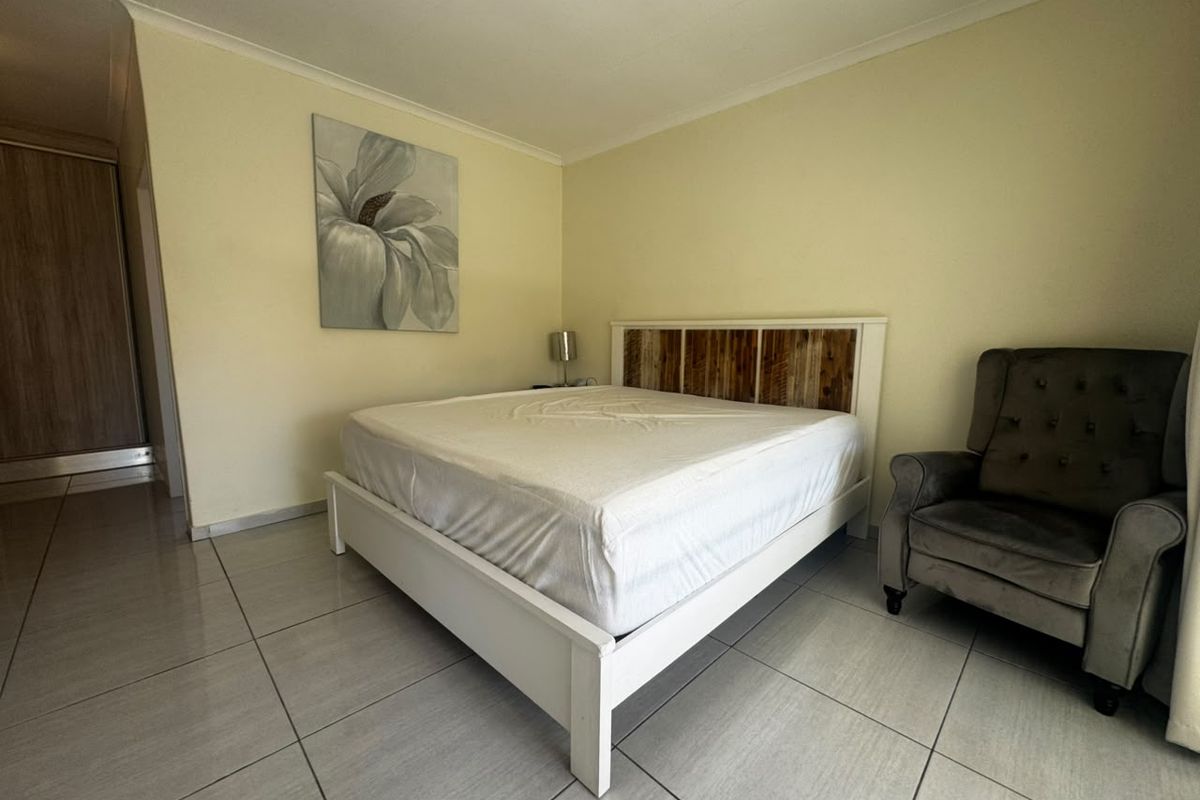 A well-maintained bedroom featuring neutral tiled flooring, coved ceilings, and a built-in wardrobe, offering a clean and functional living space.