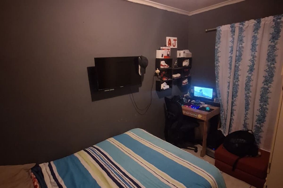 A compact bedroom featuring tiled flooring and dark painted walls, providing a functional space for rest and study.