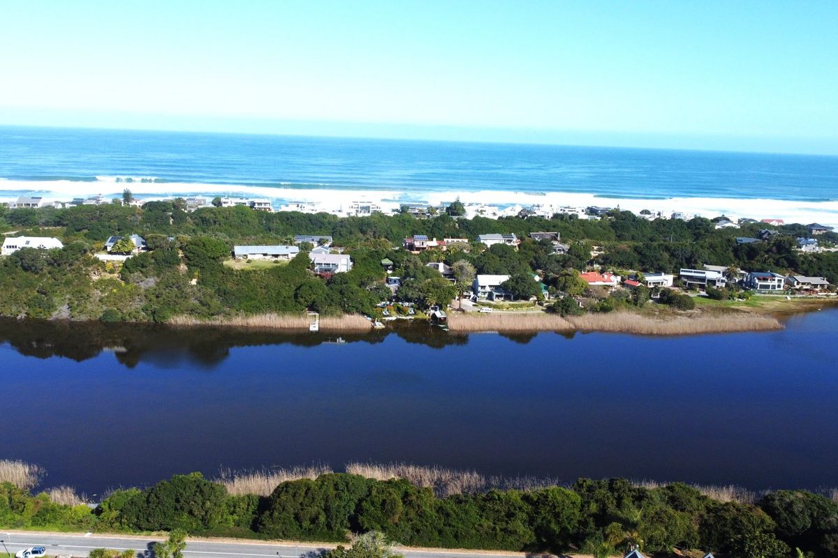 An aerial view of the coastal residential area, showcasing the estuary, surrounding natural vegetation, and proximity to the ocean.