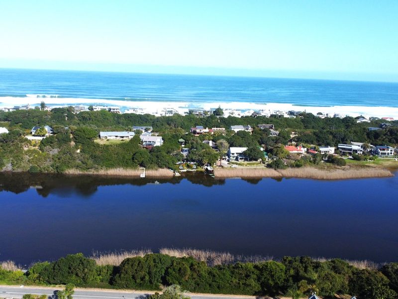 An aerial view of the coastal residential area, showcasing the estuary, surrounding natural vegetation, and proximity to the ocean.