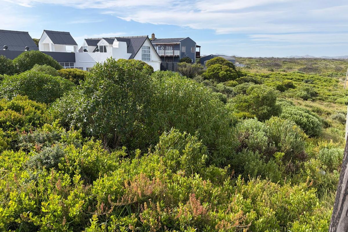 A scenic view of the natural coastal landscape and surrounding residential properties, showcasing the native vegetation and open environment of the vacant land.