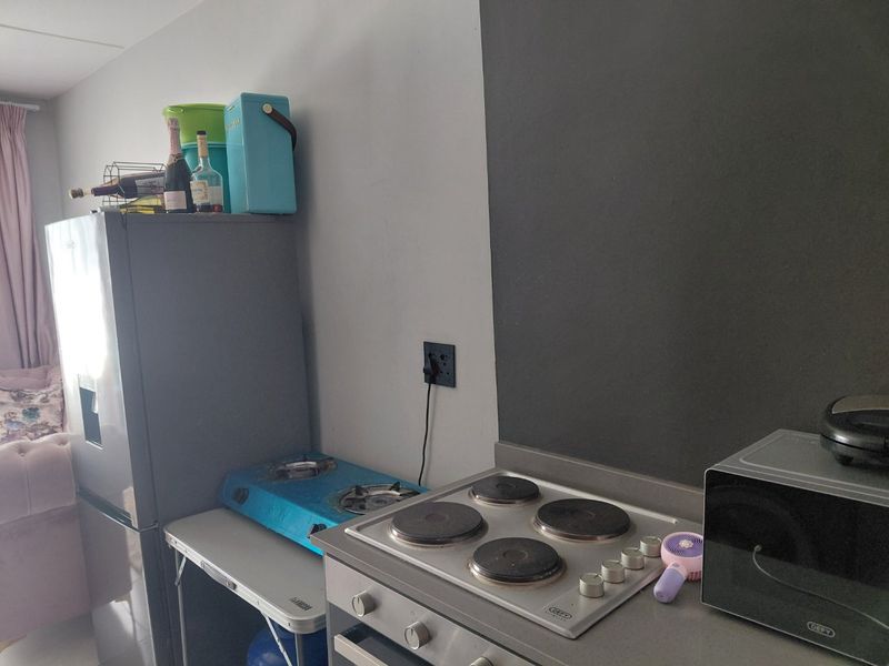 A compact kitchen area featuring a built-in electric hob, oven, and stone countertop, providing essential cooking facilities within the apartment.