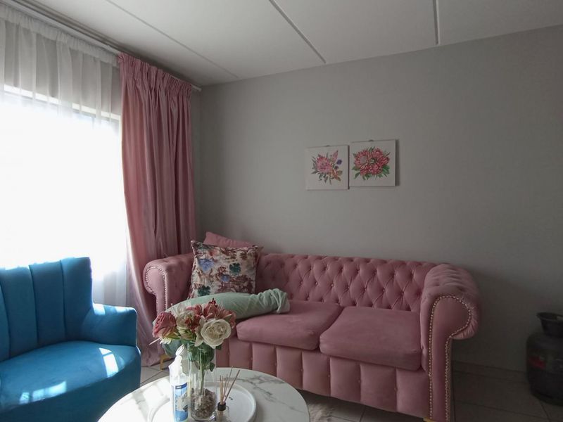 A cozy living room area featuring tiled flooring and a drop ceiling, providing a comfortable space for relaxation.