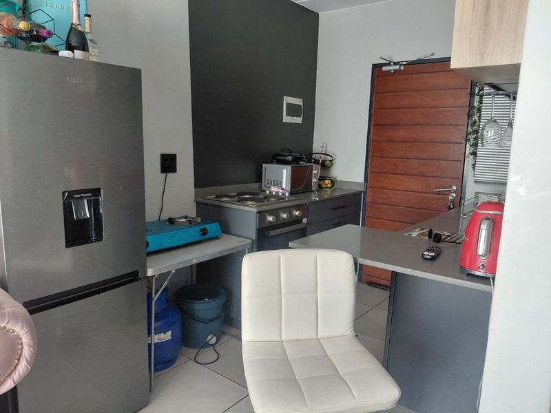 Compact kitchen area featuring built-in cabinetry, oven, hob, and tiled flooring, providing a functional space for meal preparation.