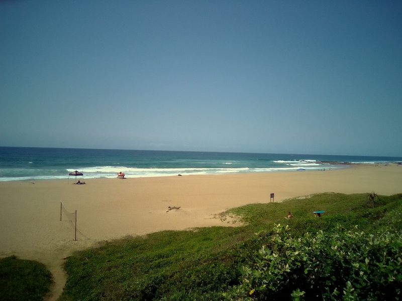 A scenic view of the sandy beach and ocean coastline, showcasing the natural surroundings of the property location.