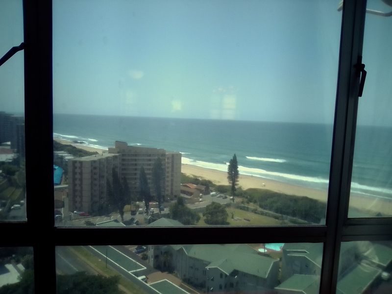 A high-level view of the coastline and beach area captured through an apartment window.