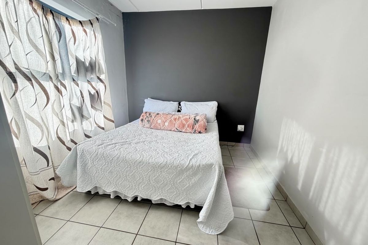 A bedroom featuring tiled flooring and a dark grey accent wall, providing a neutral base for personalization.
