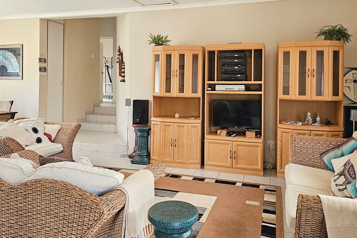 A spacious living room featuring tiled flooring and an open-plan layout with a staircase leading to the upper level.