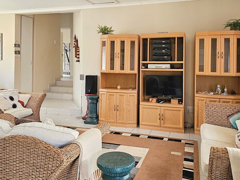A spacious living room featuring tiled flooring and an open-plan layout with a staircase leading to the upper level.