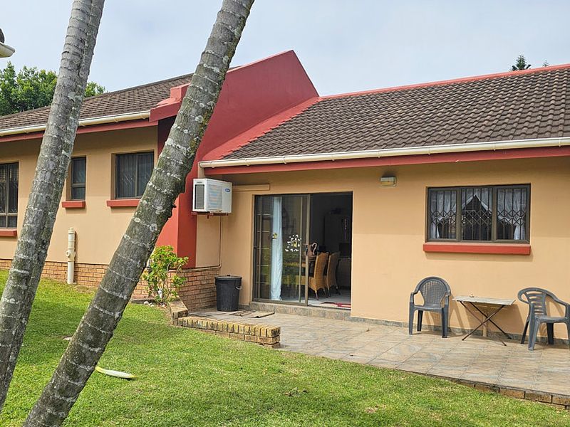 Rear view of the townhouse featuring a tiled patio area, sliding glass door access, and an external air conditioning unit set against a lawn.