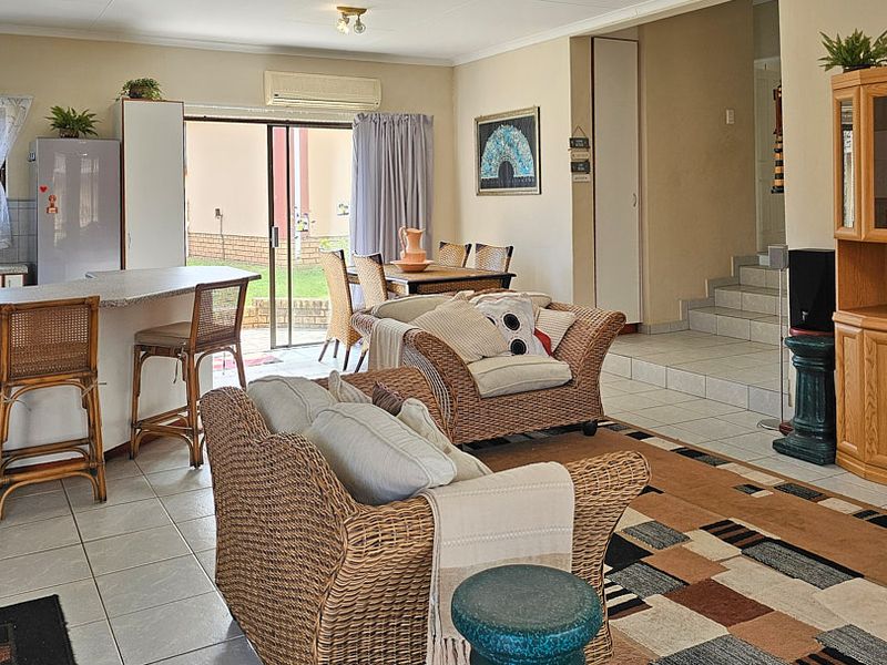 Open-plan living and kitchen area featuring tiled floors, a breakfast bar, and direct access to the rear patio through sliding glass doors.