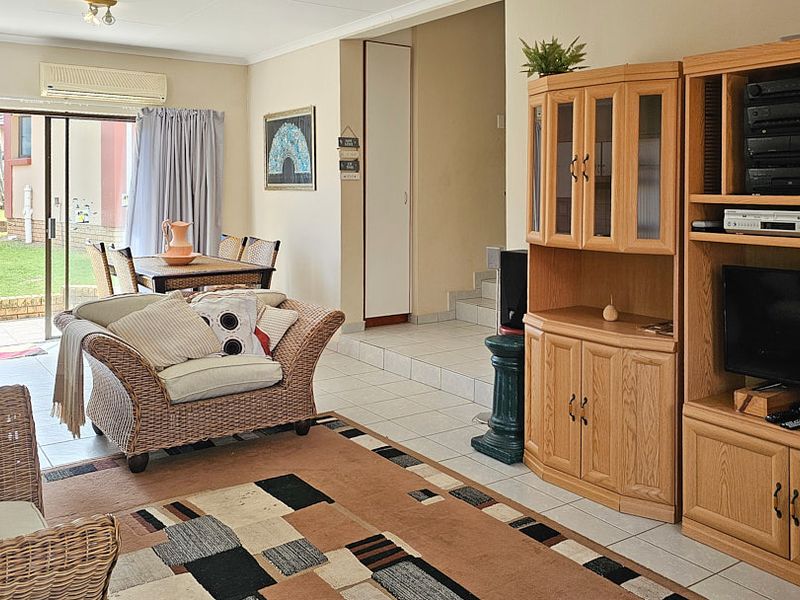 Open-plan living and dining area featuring tiled flooring, a split-system air conditioner, and direct access to an outdoor patio through sliding glass doors.