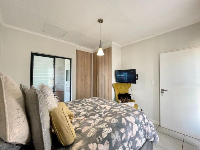 A well-maintained bedroom featuring built-in cupboards, tiled flooring, and a sliding door providing access to an adjoining space.