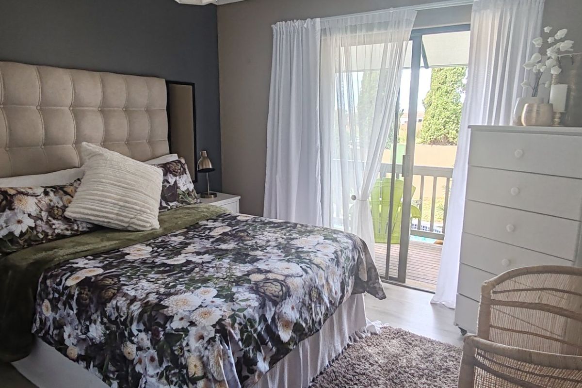 A well-maintained bedroom featuring an accent wall, laminate flooring, and a sliding glass door providing access to an outdoor balcony area.
