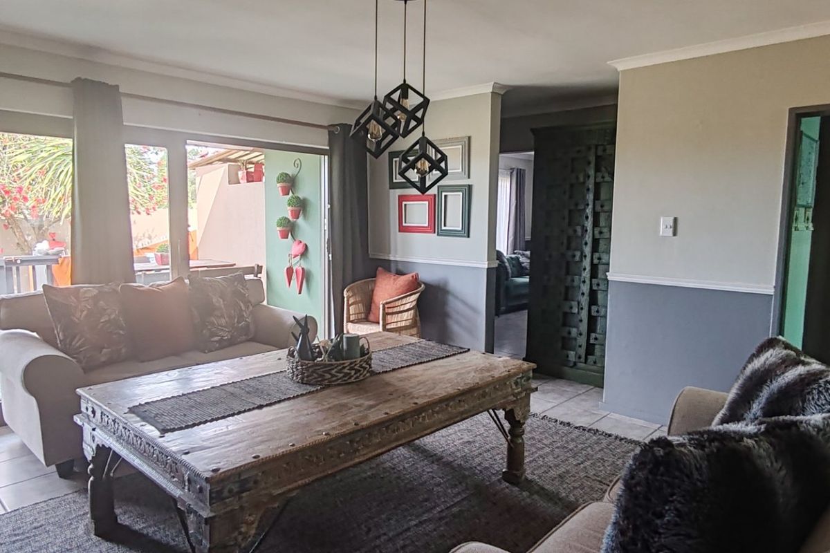 A comfortable living room featuring tiled flooring, two-tone wall finishes, and large sliding glass doors that provide access to the outdoor patio area.