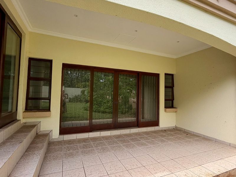 A covered patio area featuring tiled flooring and sliding glass doors providing access to the interior living space and garden view.