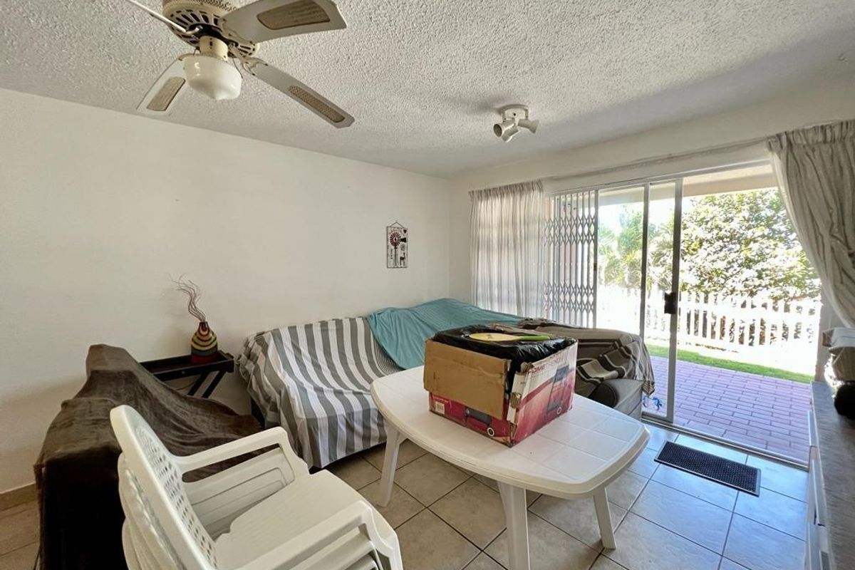 Living room featuring tiled flooring, a ceiling fan, and sliding glass doors providing access to an outdoor patio area.