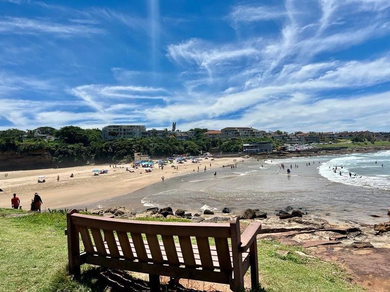 A scenic coastal view overlooking a sandy beach and ocean, showcasing the natural landscape and surrounding neighborhood.