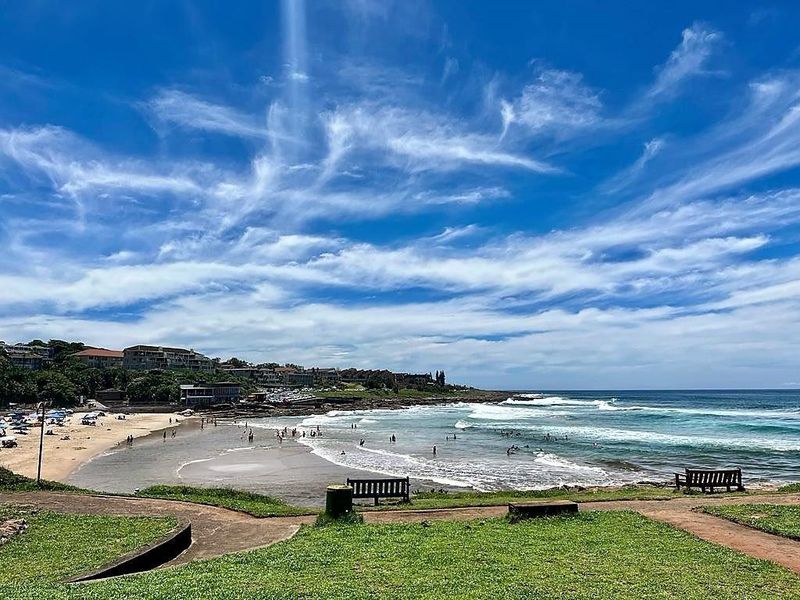A scenic coastal view overlooking the beach, ocean, and surrounding neighborhood landscape.