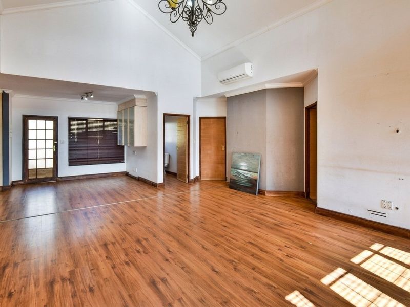Spacious living area featuring vaulted ceilings, laminate flooring, and an air conditioning unit, offering a versatile open-plan layout ready for personalization.