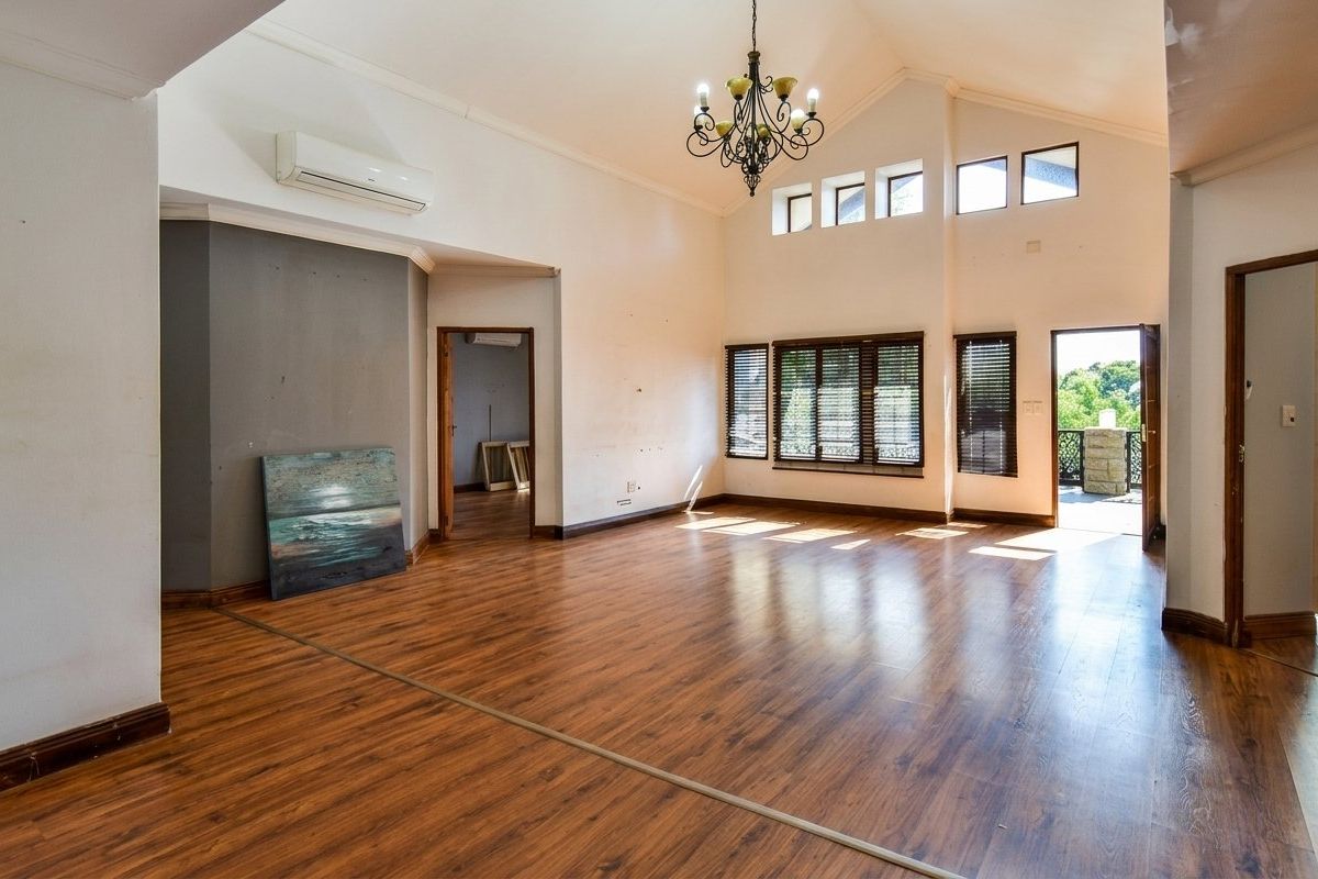 Spacious living area featuring vaulted ceilings, laminate flooring, split-system air conditioning, and abundant natural light through clerestory windows and access to an outdoor balcony.