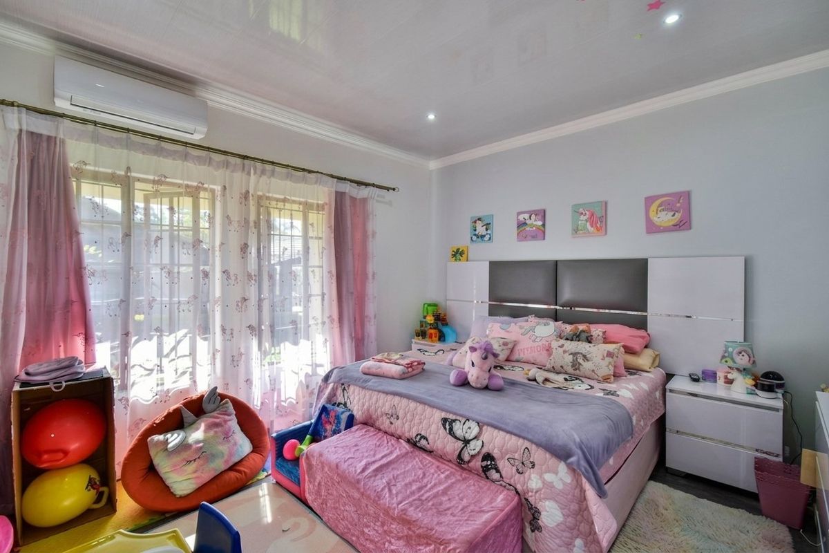 A well-maintained bedroom featuring a split-system air conditioner, recessed lighting, and sliding glass doors that provide natural light.