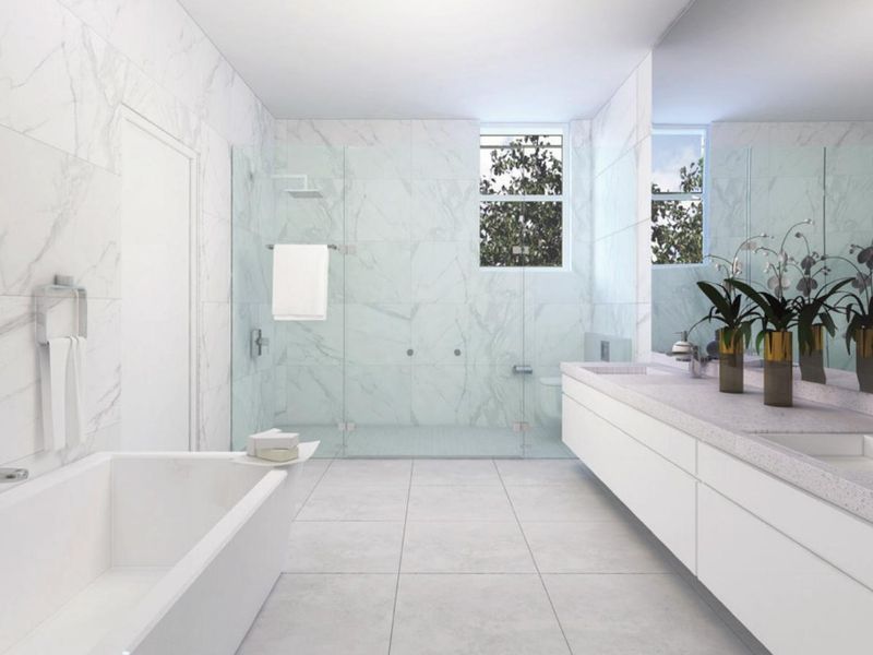 Modern, spacious bathroom featuring marble wall tiling, a large walk-in shower with glass enclosure, a double vanity, and a built-in bathtub.