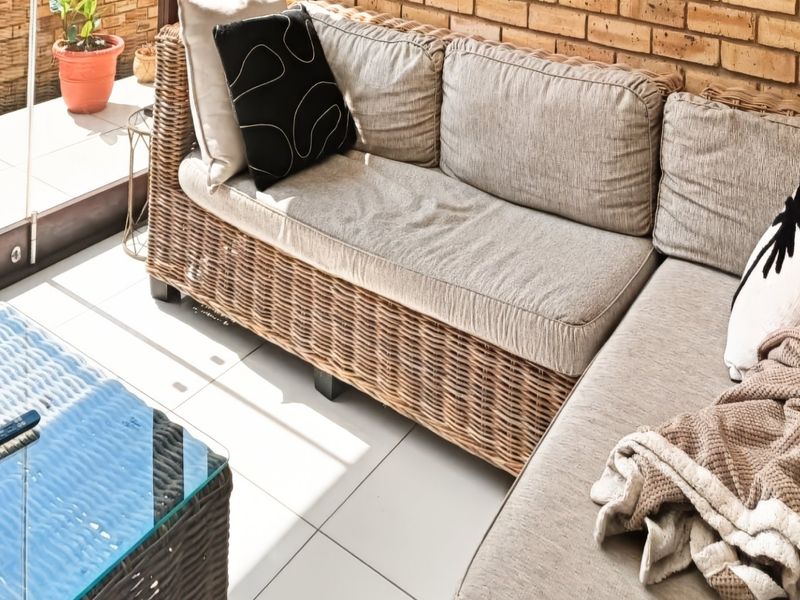 A covered patio area featuring exposed brick walls and tiled flooring, providing a comfortable outdoor living space.