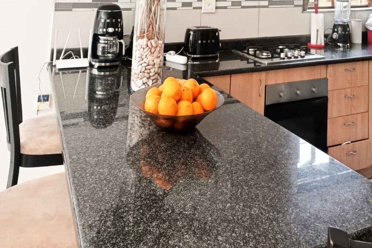 A functional kitchen featuring granite countertops, wooden cabinetry, a built-in oven, and a gas hob with a tiled backsplash.