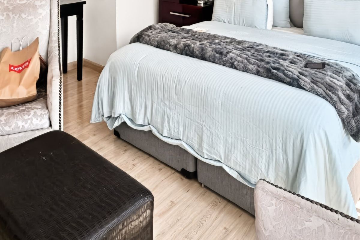 A well-maintained bedroom featuring light-toned laminate flooring and a neutral color palette.