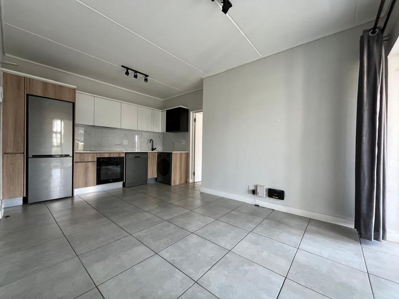 Modern open-plan living area featuring a contemporary kitchen with sleek cabinetry, marble-look splashback, and tiled flooring throughout.