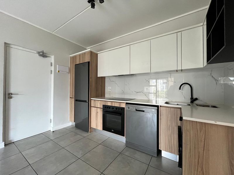 Modern kitchen featuring sleek white and wood-grain cabinetry, stone countertops, marble-look splashback, and integrated appliances including an oven and hob.