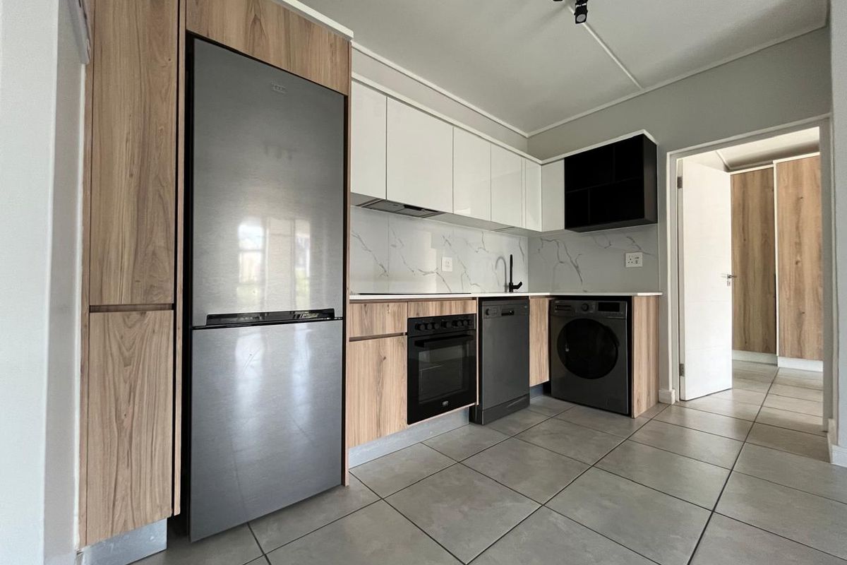 Modern kitchen featuring sleek wood-grain and white cabinetry, marble-look splashback, integrated appliances, and contemporary track lighting.