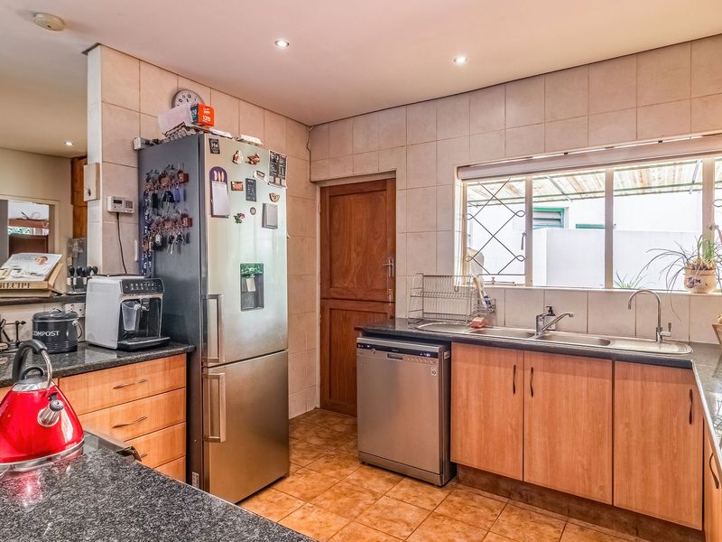 A functional kitchen featuring granite countertops, double basin sink, tiled backsplash, and ample built-in cabinetry with recessed lighting.