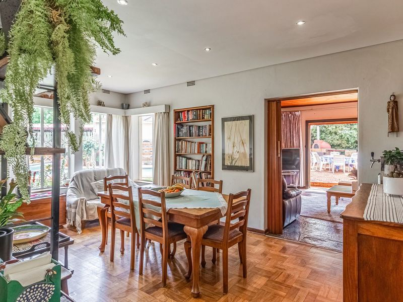 A dining room featuring warm parquet flooring, recessed lighting, and built-in shelving, with a sliding door providing access to an outdoor patio area.