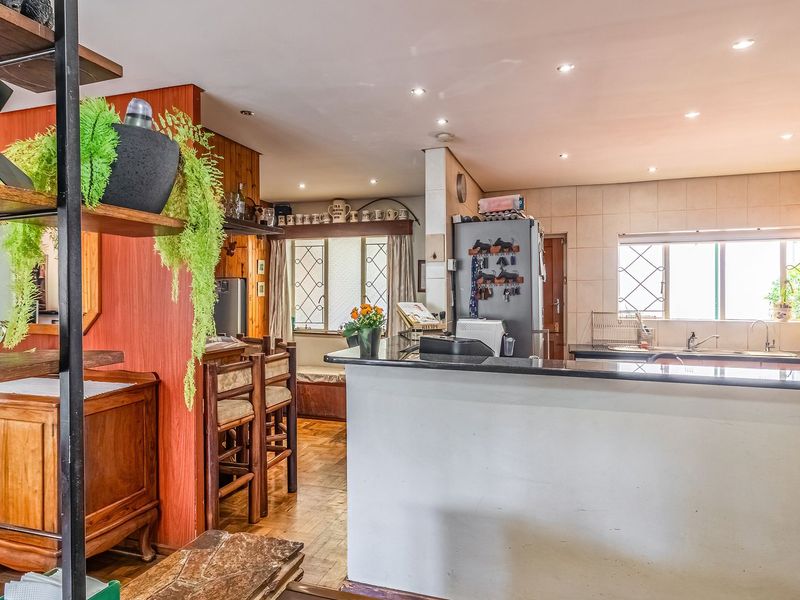 Open plan kitchen and living area featuring granite countertops, wooden cabinetry, and parquet flooring, offering a functional layout with integrated breakfast bar.