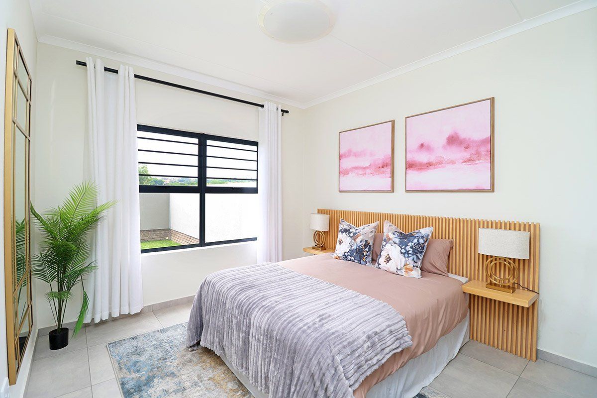 A well-maintained bedroom featuring tiled flooring, a modern slatted timber headboard with integrated bedside shelves, and a black aluminium window frame.