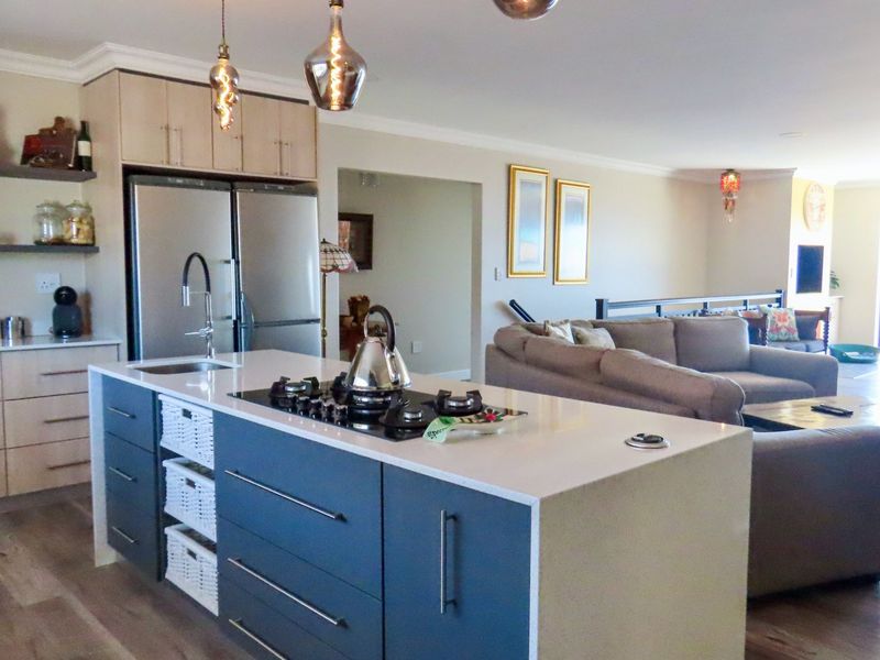 Spacious open-plan living area featuring a modern kitchen with a central island, stone countertops, gas cooktop, and integrated cabinetry flowing into the dining space.