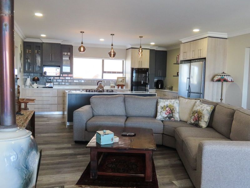 Spacious open-plan living area featuring a modern kitchen with island, built-in cabinetry, and a cozy freestanding fireplace, finished with contemporary laminate flooring.