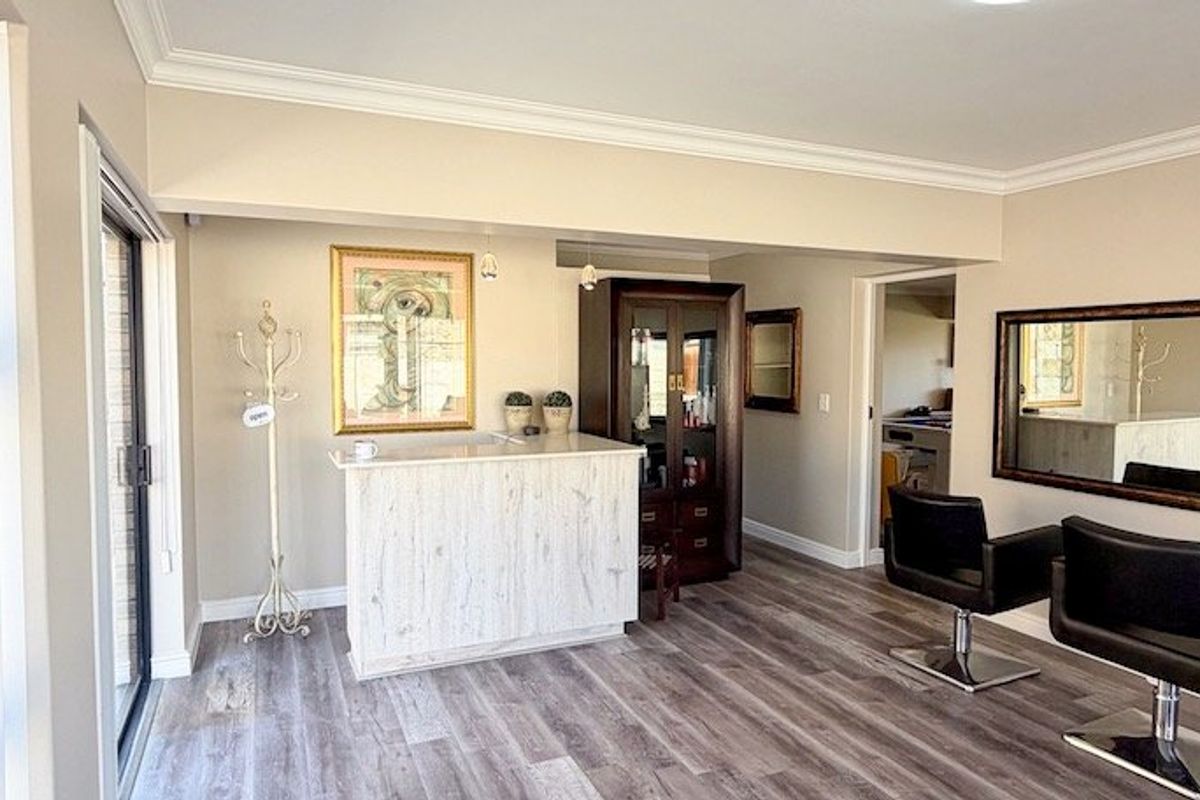 A well-maintained living area featuring modern laminate flooring, crown molding, and a sliding glass door providing natural light.