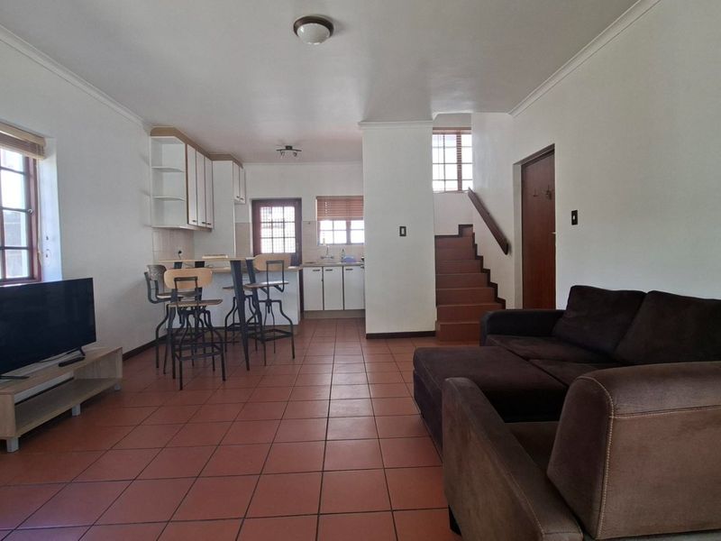 Open plan living and kitchen area featuring tiled flooring, built-in cabinetry, and a staircase leading to the upper level.