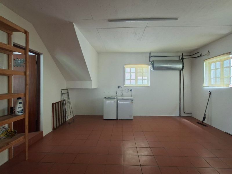 A functional laundry room featuring tiled flooring, plumbing connections for appliances, and an exposed geyser unit.