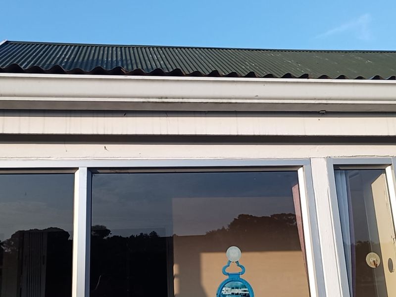 Exterior view of the property showing the corrugated metal roof, guttering, and aluminium window frames.