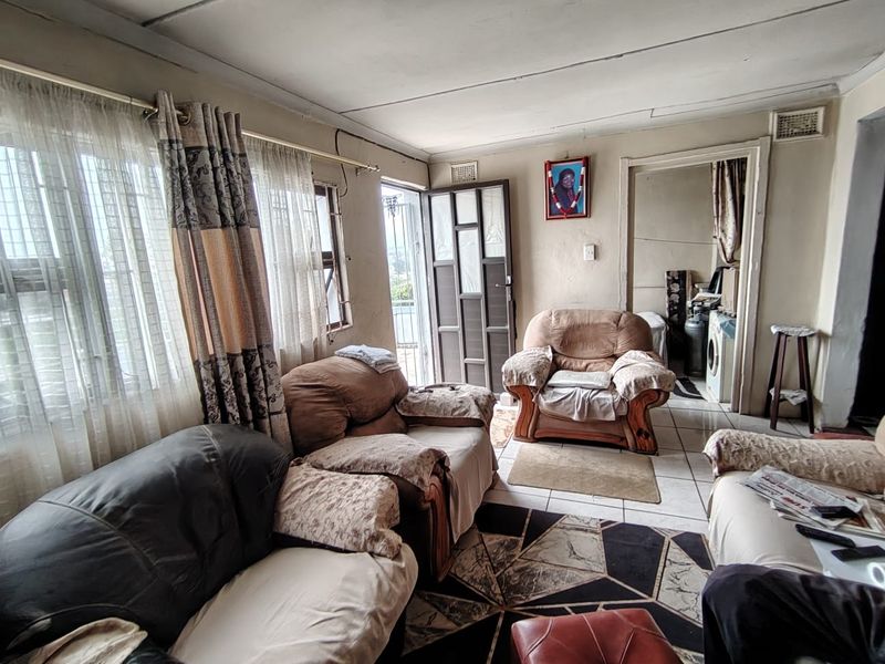 A living room area featuring tiled flooring and a security gate, showing signs of wear and requiring cosmetic updates to improve the overall aesthetic.