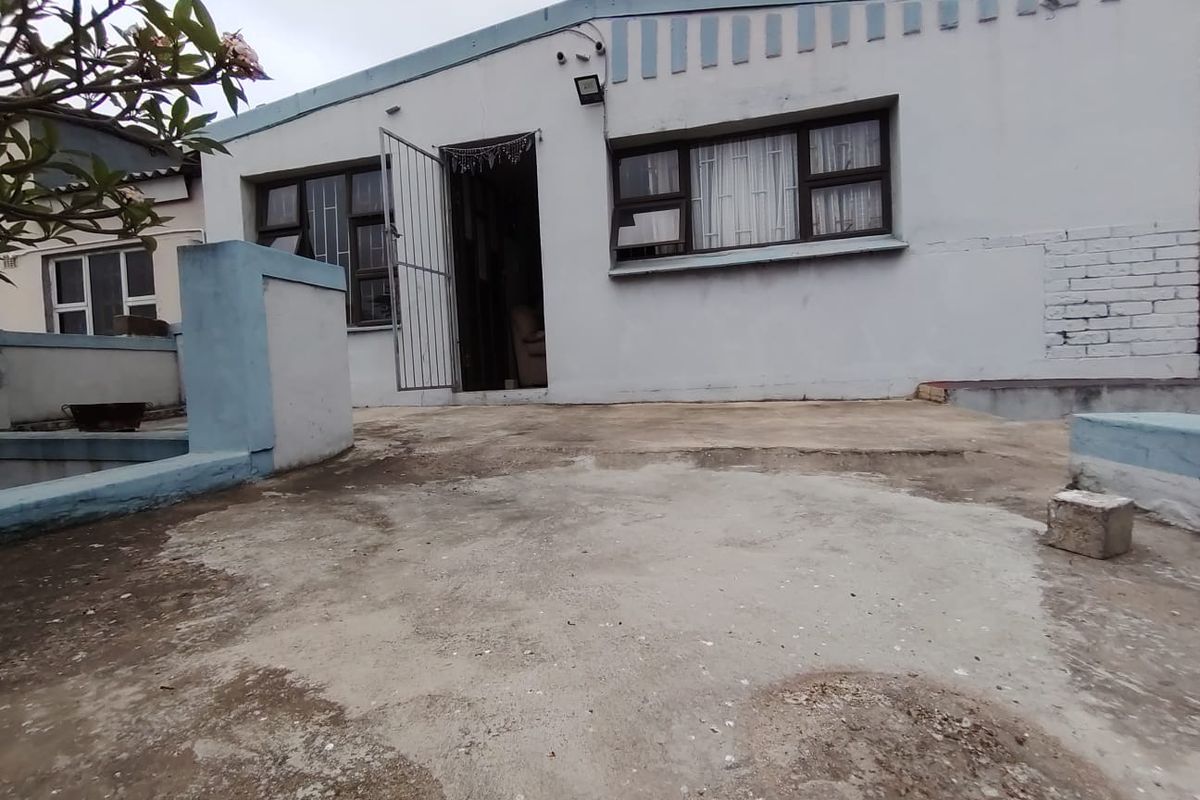 Rear exterior view of the house featuring a concrete patio area, security gates, and security bars on the windows.