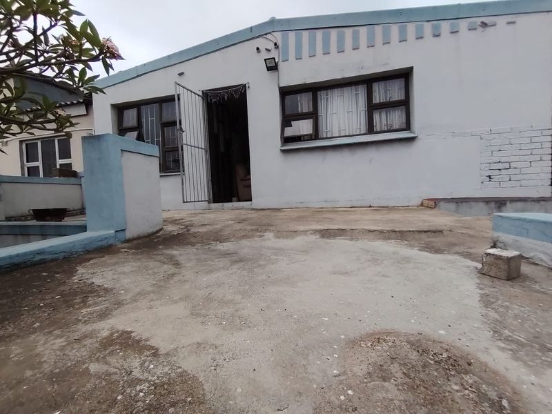 Rear exterior view of the house featuring a concrete patio area, security gates, and security bars on the windows.