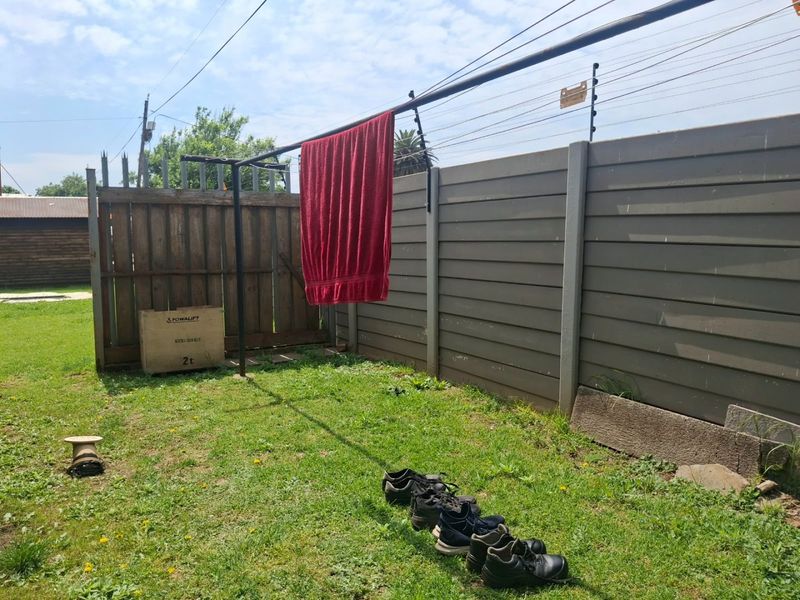 A private garden area featuring a precast concrete boundary wall with electric fencing and a metal washing line.