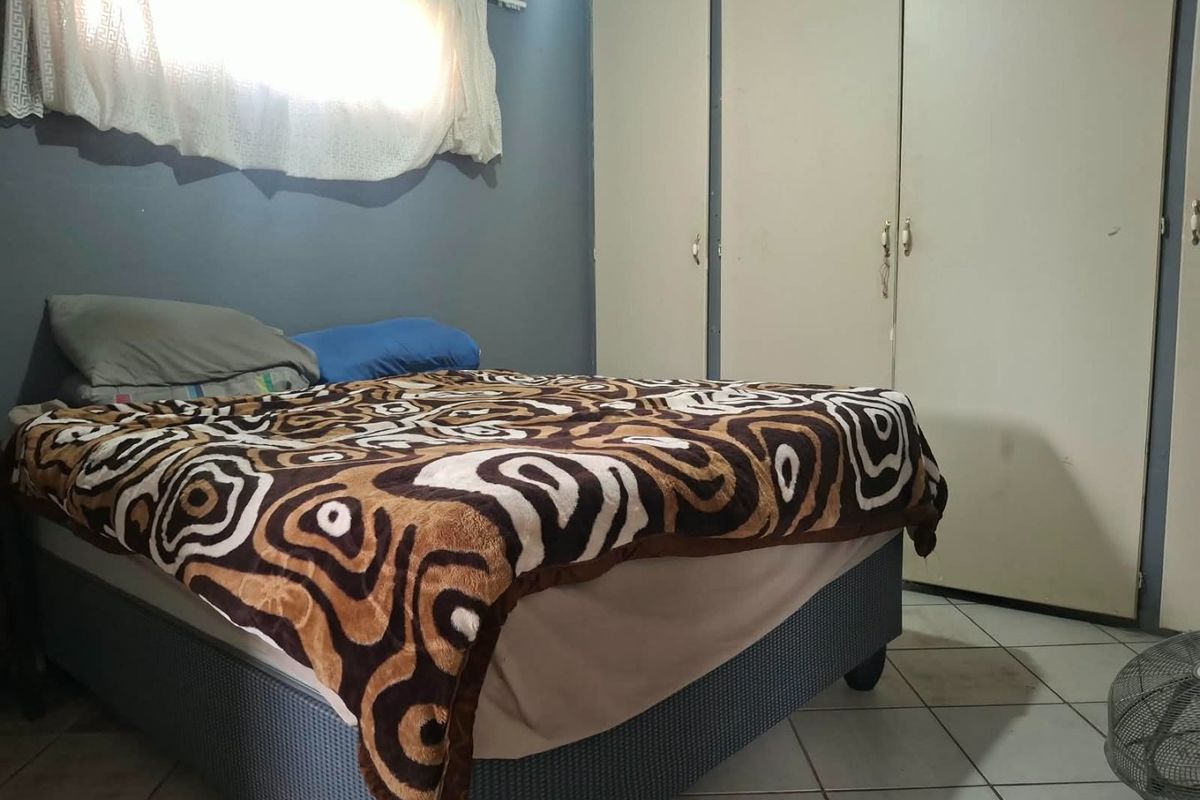 A bedroom featuring built-in cupboards and tiled flooring, requiring cosmetic updates to improve its overall condition and appeal.