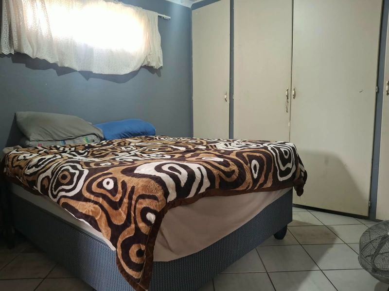 A bedroom featuring built-in cupboards and tiled flooring, requiring cosmetic updates to improve its overall condition and appeal.